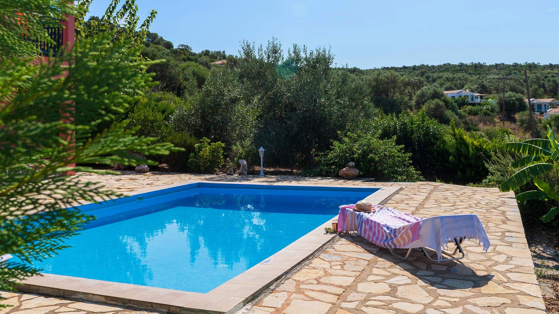 Ligbedje aan zwembad omringd door groen