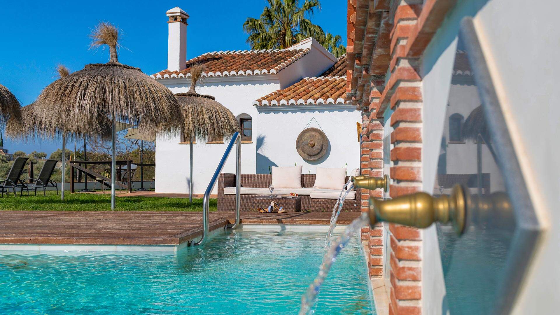 witte villa met rieten parasols en zwembad