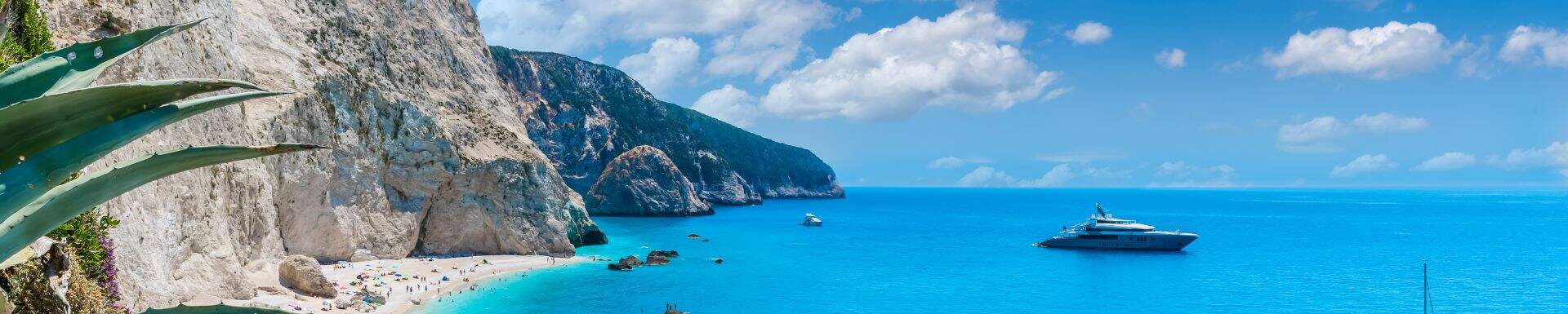 Strand op Lefkas met een jacht in de helderblauwe zee
