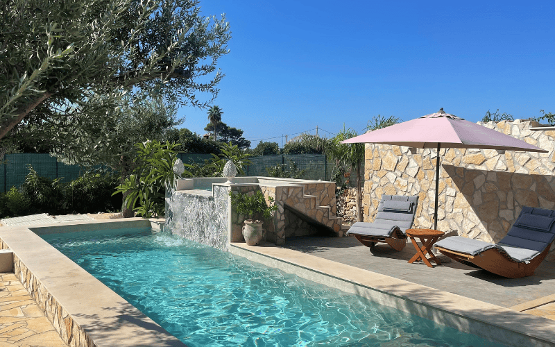 Zwembad met ligstoelen en parasol omringd door grote olijfbomen en groen - casa pomelia, sicilie