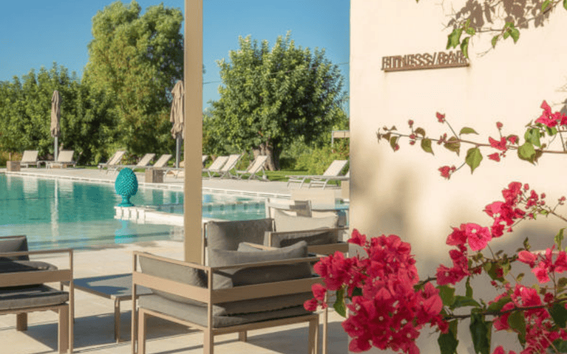 Zithoek en zwembad omringd door roze bloemen en groen