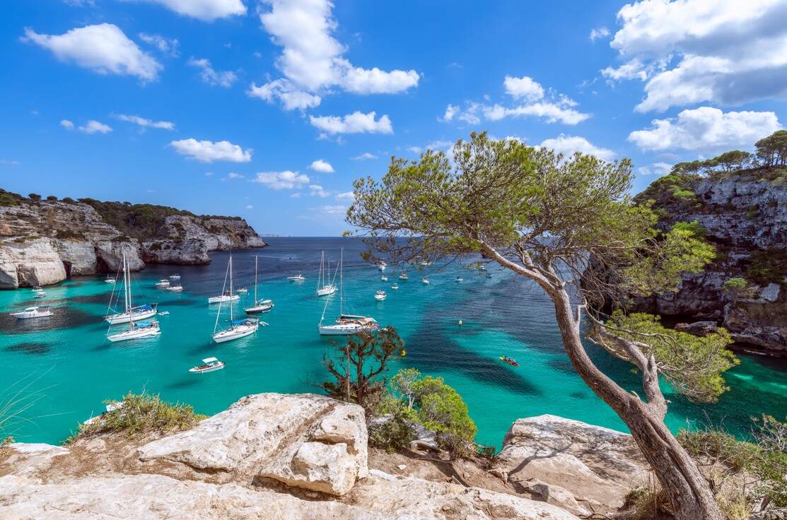 Helderblauwe zee bij Menorca met een aantal bootjes in het water