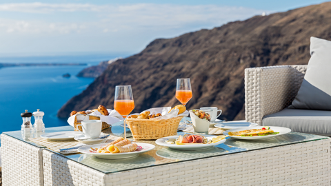 Gedekte ontbijttafel met uitzicht op zee en bergen