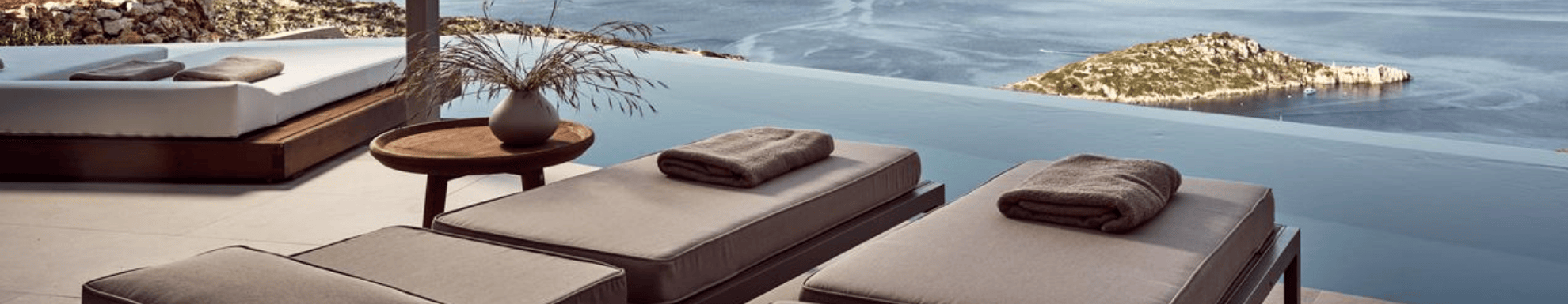 Twee ligbedden met een infinitypool en uitzicht op zee